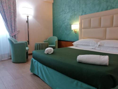 una camera d'albergo con letto e copriletto verde di Hotel Principe a Pomezia