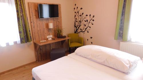 um quarto com uma cama, uma secretária e uma televisão em Gasthof Grüner Baum em Oberlangfurth