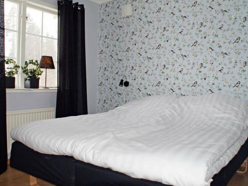 a bedroom with a white bed with a floral wallpaper at Two-Bedroom Holiday home in Håcksvik 2 in Håcksvik