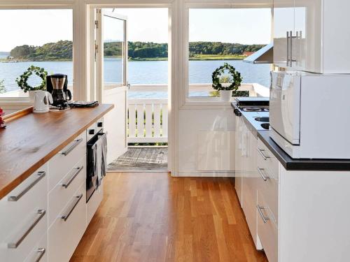 a kitchen with white cabinets and a view of the water at 6 person holiday home in kode in Kode