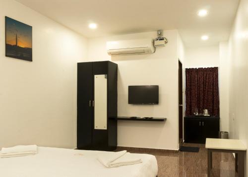 1 dormitorio con 1 cama y TV en la pared en COSY CHAMBRE, en Pondicherry