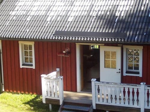 een rood huis met een witte veranda en een deur bij 6 person holiday home in TORSBY in Överbyn