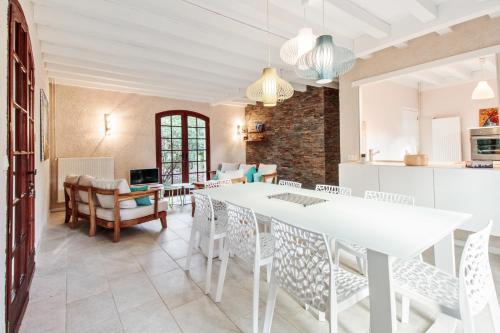 une cuisine et une salle à manger avec une table et des chaises blanches dans l'établissement Villa 8 personnes La Dryade, à Seignosse