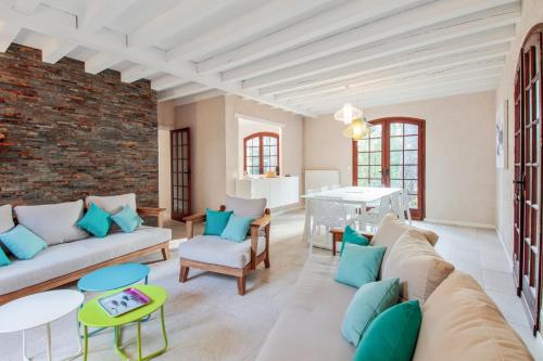 ein Wohnzimmer mit einem Sofa, Stühlen und einer Ziegelwand in der Unterkunft Villa 8 personnes La Dryade in Seignosse