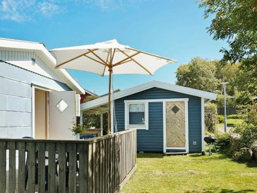 une maison bleue avec un parasol dans la cour dans l'établissement 6 person holiday home in FALKENBERG, à Falkenberg