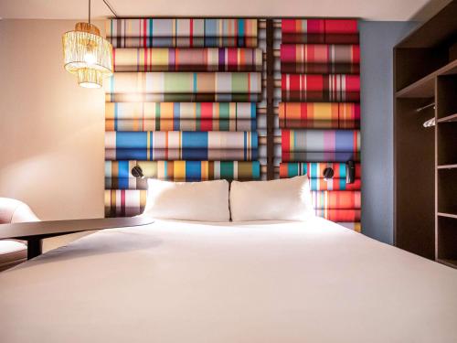 1 dormitorio con 1 cama y una pared colorida en ibis Styles Perpignan Centre Gare en Perpiñán