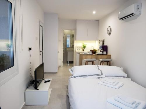 a white bedroom with a bed and a television at Modern & Cozy Studio w/ Backyard Near City Center in Limassol