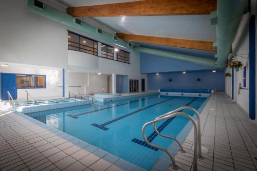 a large swimming pool with blue walls and wooden ceilings at Clifden Station House Hotel in Clifden