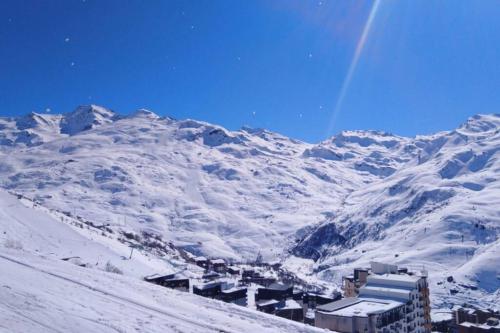 a snow covered mountain with a town in front of it at Les Ménuires - Appart 2 pièces 4 pers - Balcon plein SUD - Ski aux pieds in Les Menuires