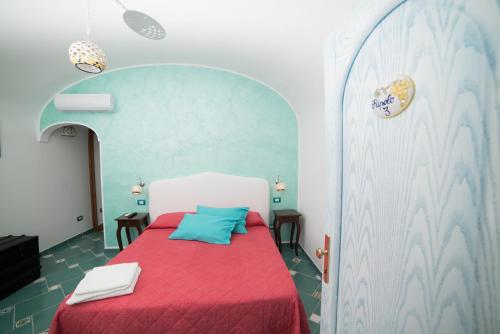 a bedroom with a bed with a red blanket and blue pillow at San Giacomo Relais in Furore
