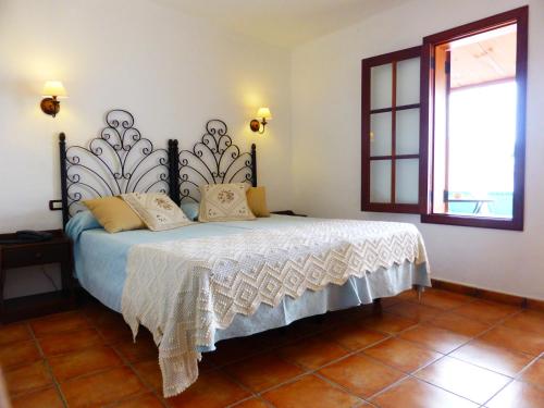 a bedroom with a bed with white sheets and a window at Hotel Rural El Navío - Adults Only in Alcalá