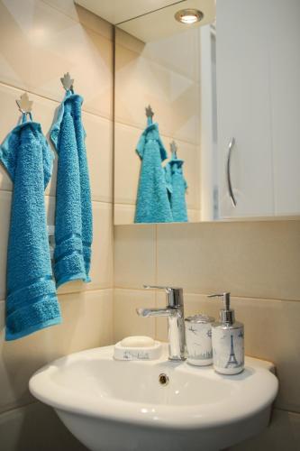 a bathroom with a sink and a mirror and blue towels at Studio Apartments KIM - Dilberovic in Mostar