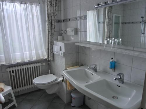 a white bathroom with a sink and a toilet at Hotel Resi von der Post in Bad Wiessee