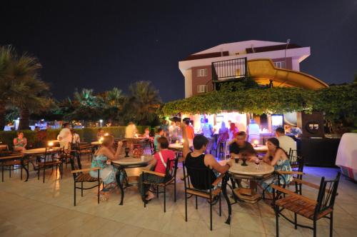 a group of people sitting at tables at a restaurant at night at Camyuva Beach Hotel in Kemer