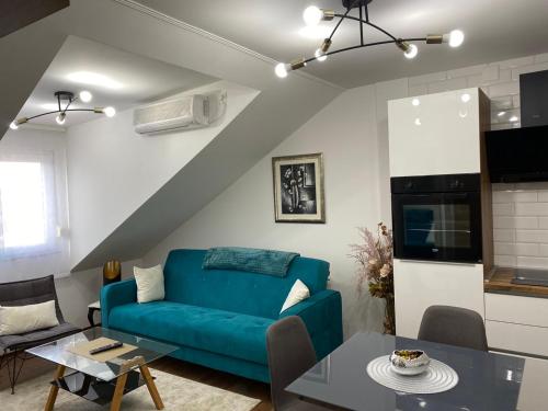 a living room with a blue couch and a table at APARTMAN PAVIĆ in Vinkovci