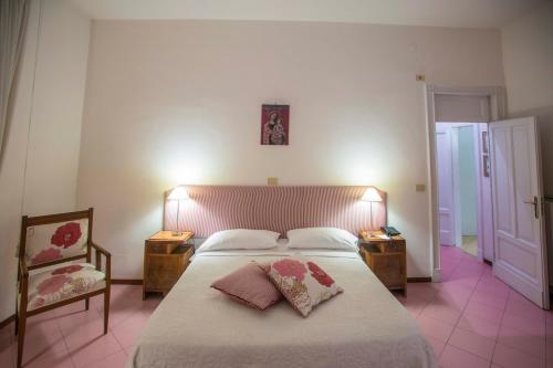 a bedroom with a large bed with two tables and a chair at Hotel Victoria Maiorino in Cava deʼ Tirreni