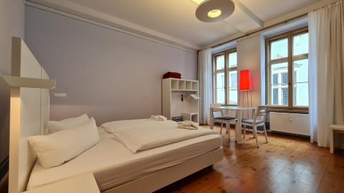 a white bedroom with a bed and a table at Hotel Cranach-Herberge City Centre in Lutherstadt Wittenberg