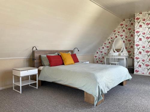 1 dormitorio con 1 cama con almohadas rojas y amarillas en De Boerderij - Buitenplaats Ruitenveen, privé, en Nieuwleusen