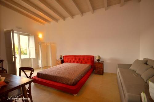 a bedroom with a red bed and a couch at Masseria La Lizza - Ospitalità Rurale in Lecce