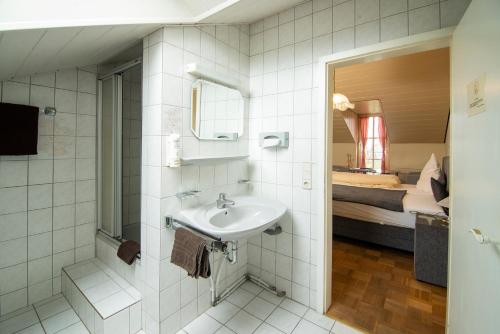 a bathroom with a sink and a bedroom at Zum Bergischen Hof in Dormagen