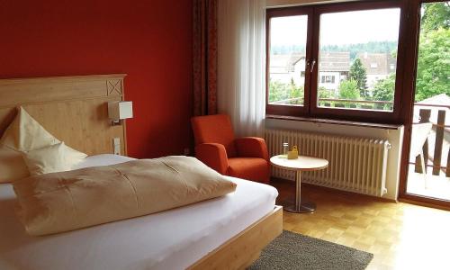a bedroom with a bed and a chair and a window at Hotel & Restaurant Krone in Waldbronn