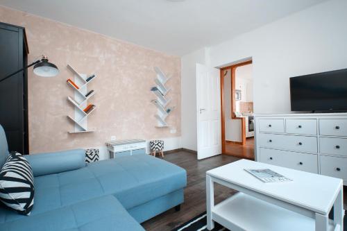 a living room with a blue couch and a tv at Aquilo Apartmanok in Tihany