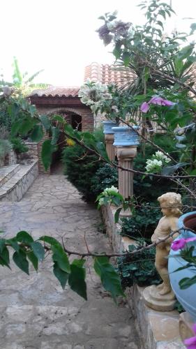 um jardim com um caminho de pedra com flores e uma estátua em Mila LA villa em Kástro Tornéze