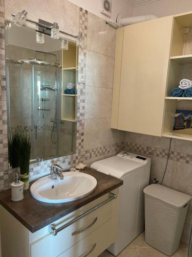a bathroom with a sink and a washing machine at Piano Balaton Apartment in Zamárdi