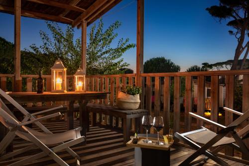 eine Terrasse mit einem Tisch, Stühlen und Lampen in der Unterkunft Parco Della Gallinara in Lido dei Pini