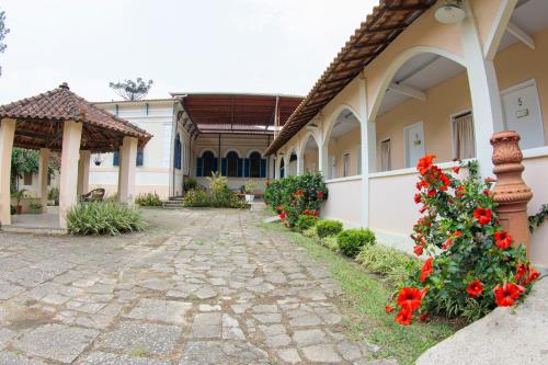 a courtyard of a house with red flowers at Pousada Vale do Café in Ipiabas