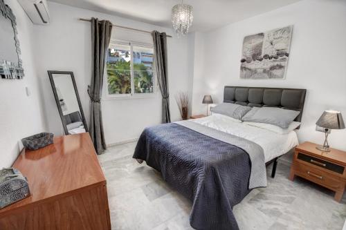 een slaapkamer met een bed, een tafel en een spiegel bij TIMON II, Luxury 3 bedroom Beachside Apartment in Benalmádena
