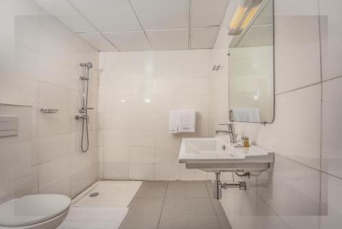 a white bathroom with a toilet and a sink at AKWA HIN Douala in Douala