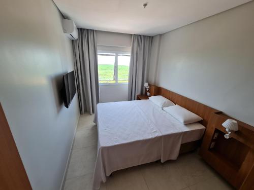 une chambre avec un lit blanc et une fenêtre dans l'établissement Salinas Exclusive Resort, à Salinópolis
