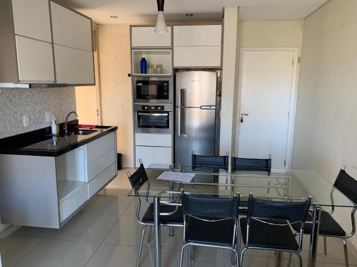 a kitchen with a table and chairs and a refrigerator at Apartamento Decorado in Guarujá