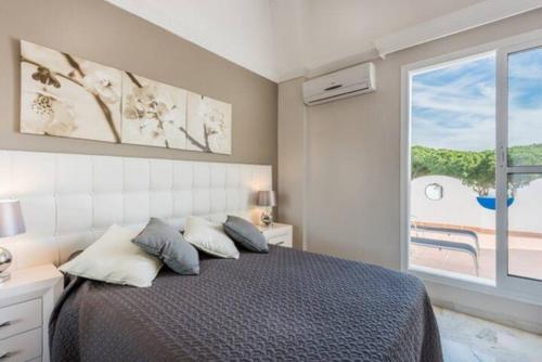 een slaapkamer met een bed en een groot raam bij Casa Kava Superior ApartHotel Resort Near Cabopino NO CAR NEEDED in Marbella