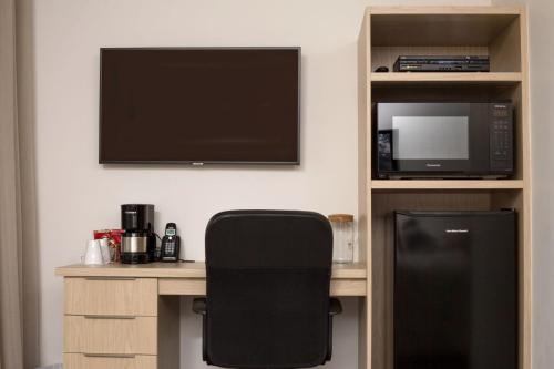 a room with a desk with a microwave and a tv at Motel Blanche d'Haberville in Saint-Jean-Port-Joli