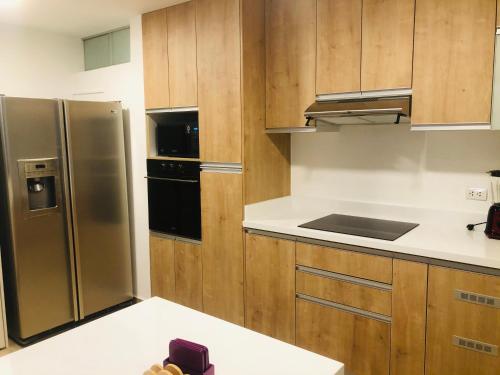 a kitchen with wooden cabinets and a stainless steel refrigerator at Brand New Apartment in Barranco in Lima