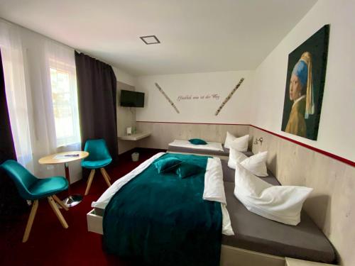 a bedroom with a large bed and blue chairs at Hotel Wilder Mann in Feuchtwangen