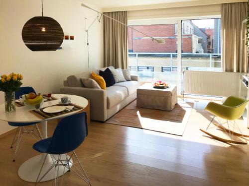 a living room with a couch and a table and chairs at Studio zee in Nieuwpoort