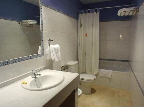 een badkamer met een wastafel, een toilet en een spiegel bij Hostal Emilia in Trujillo