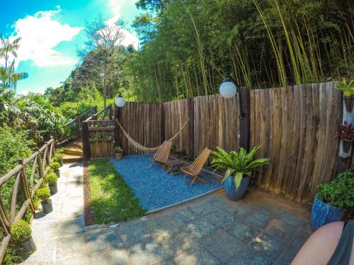 a backyard with two chairs and a fence at Pousada Nova Gironda in Paty do Alferes