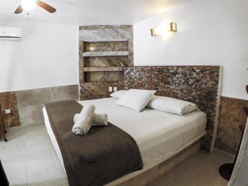 a white bed sitting in a bedroom next to a wall at La Casa de las Lunas in Chichén-Itzá
