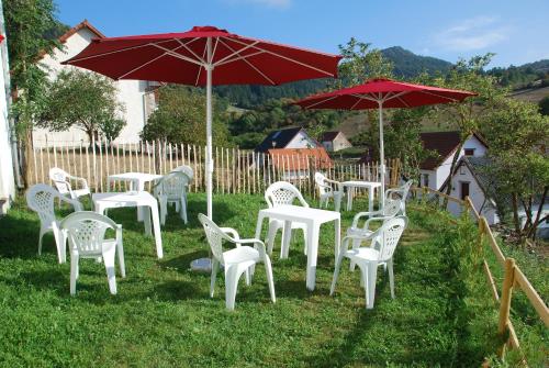 un gruppo di tavoli e sedie bianchi con ombrelloni rossi di Posada Sarigarri ad Abaurrea Baja