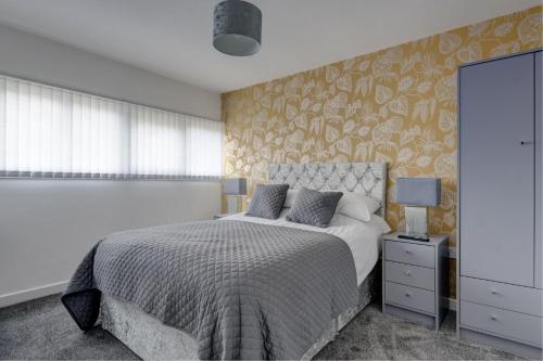 a bedroom with a bed with a floral accent wall at Sunderland Self Catering 4 - City Centre Townhouse with free parking in Sunderland