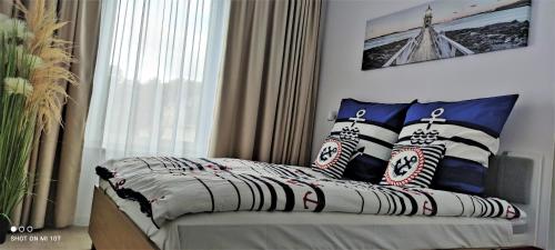 1 dormitorio con cama con almohadas y ventana en Apartament Morski - Olimpijska 2, Mielno, en Mielno