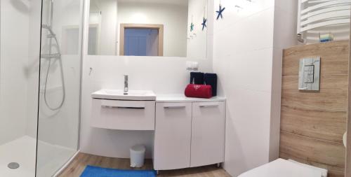 ein weißes Bad mit einem Waschbecken und einer Dusche in der Unterkunft Apartament Morski - Olimpijska 2, Mielno in Mielno