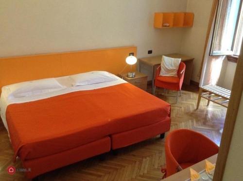 1 dormitorio con 1 cama de color naranja, mesa y sillas en Affittacamere ACCASA, en Prato