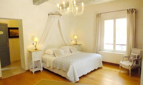 - une chambre blanche avec un lit et un lustre dans l'établissement La Royante, à Aubagne