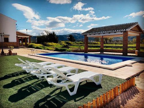 - un groupe de chaises longues blanches à côté de la piscine dans l'établissement Casa Rural Huerta Abuela María, à Archidona