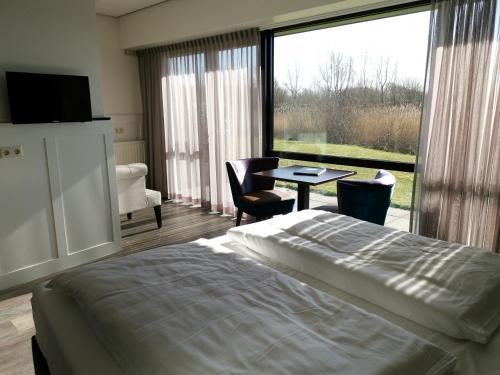 a bedroom with a bed and a table and a large window at Resort Land & Zee in Scharendijke